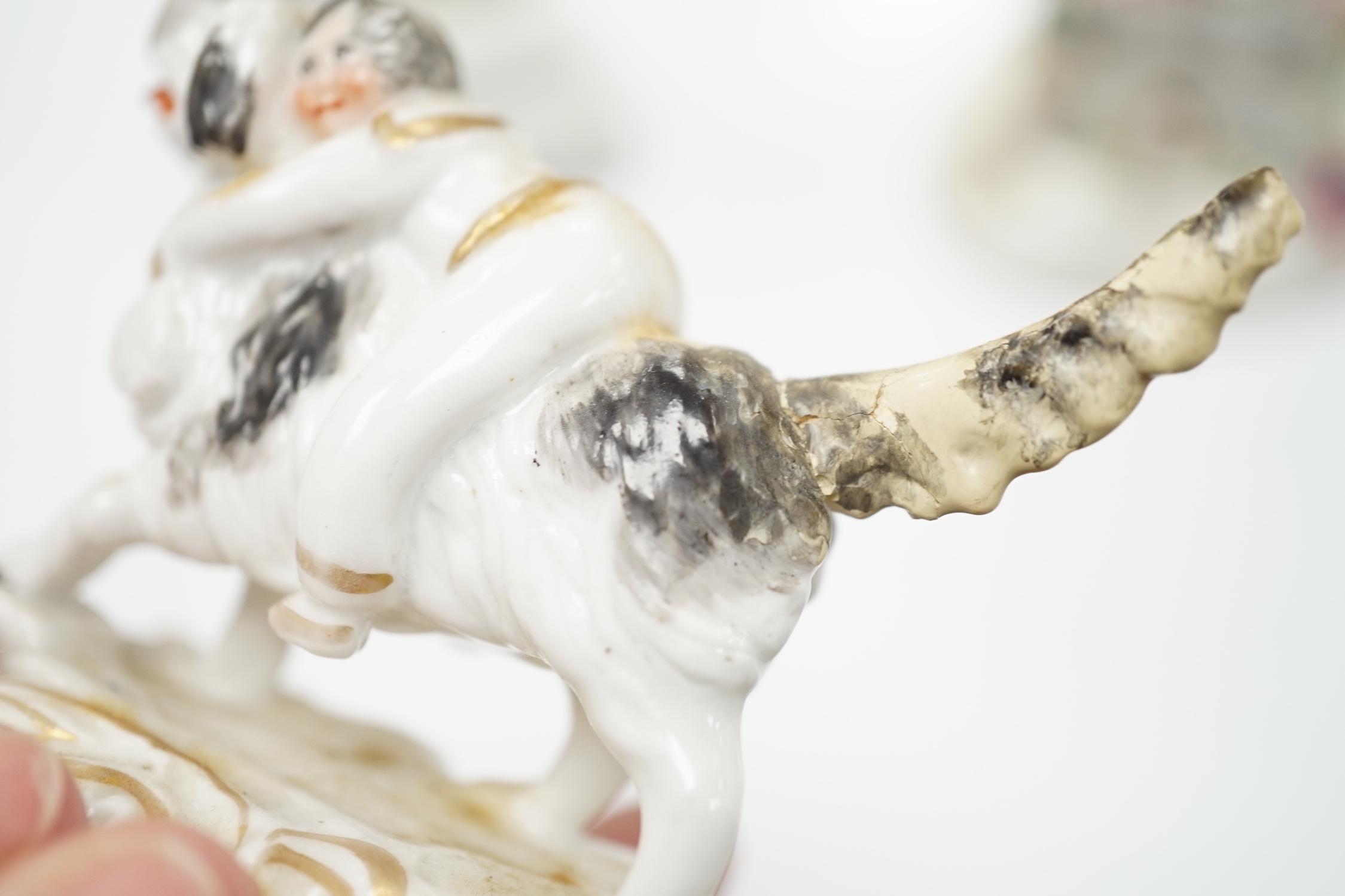 Three Staffordshire porcelain dog figures, c.1830-50, comprising a boy clinging to the back of a spaniel, a model of a poodle with a bird in its mouth and a model of a cottage with a small dog in the doorway, tallest 9cm